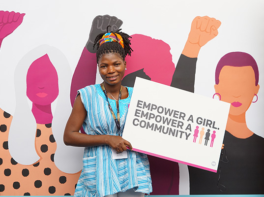 Dorcas with ‘Empower a girl, empower a community’ placard