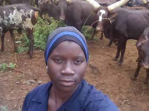 Mariam standing in a field with cattle