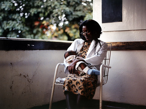Runyararo sitting holding an infant patient
