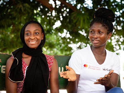 Husina sitting with CAMFED Association member Hannah