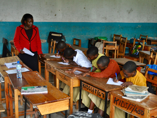 Vumilia and her classmates complete forms identifying their school needs to Camfed